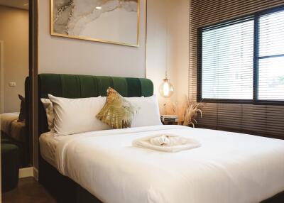 cozy modern bedroom with green headboard, abstract wall art, large window, and bedside lamp