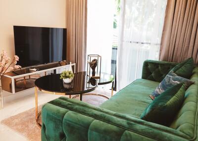 Modern living room with green velvet sofa and large TV