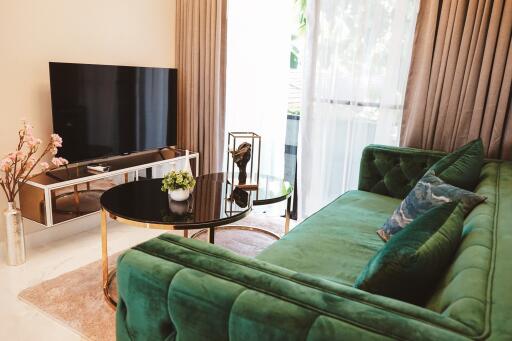 Modern living room with green velvet sofa and large TV