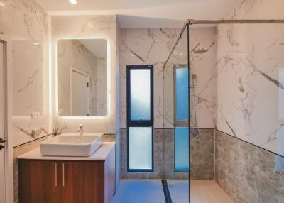 Modern bathroom with a walk-in shower, vanity, and large illuminated mirror