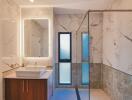 Modern bathroom with a walk-in shower, vanity, and large illuminated mirror