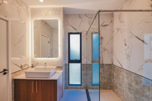 Modern bathroom with a walk-in shower, vanity, and large illuminated mirror