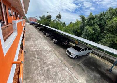 View of parking area with multiple parked cars next to an orange building