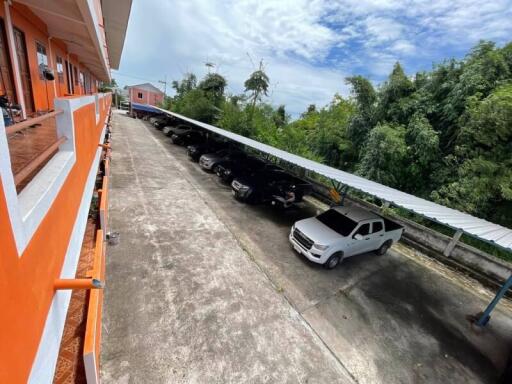 View of parking area with multiple parked cars next to an orange building