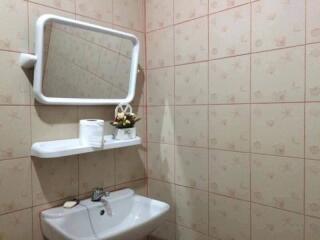 Bathroom with tiled walls, mirror, sink, and shelf