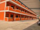 Orange multi-level apartment building with parking area