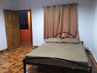 Bedroom with wooden door and large window with curtains