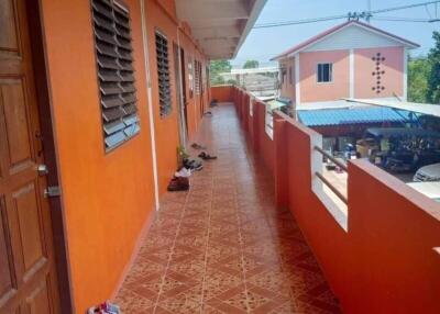 Exterior walkway of an apartment building with orange walls and a tiled floor