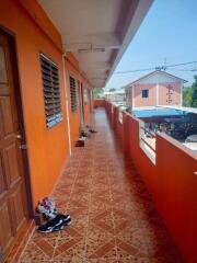 Exterior walkway of an apartment building with orange walls and a tiled floor