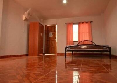 Spacious bedroom with tiled floor, a bed, wardrobe, and a window with curtains