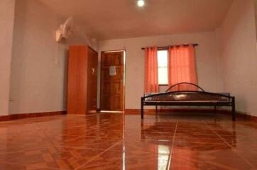 Spacious bedroom with tiled floor, a bed, wardrobe, and a window with curtains