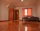 Spacious bedroom with tiled floor, a bed, wardrobe, and a window with curtains