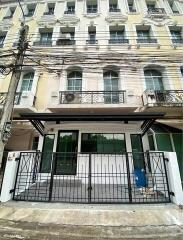 Exterior view of a multi-story residential building with a black metal fence