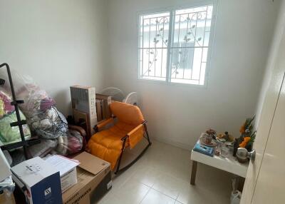 Small room used for storage with a window, boxes, orange chair, and a small table