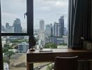 View of cityscape from bedroom with large window, desk, and chair