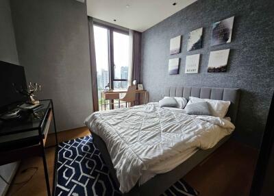 Modern bedroom with large windows, a bed, desk, and wall decor