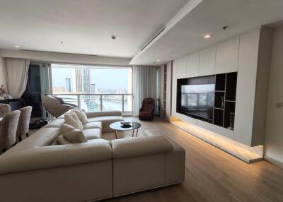 Modern living room with large windows, sectional sofa, wall-mounted TV, and city view