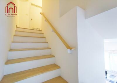 Staircase with wooden steps and white walls leading to upper floor