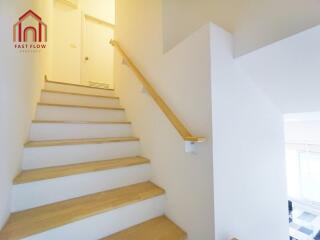 Staircase with wooden steps and white walls leading to upper floor