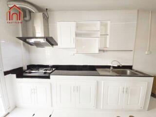 Modern kitchen with white cabinets, black countertops, and stainless steel appliances