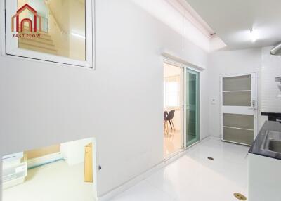 Bright kitchen area with white tiles connected to dining space