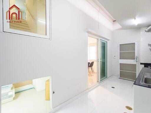 Bright kitchen area with white tiles connected to dining space