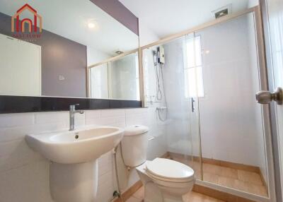 A modern bathroom with a glass shower enclosure, toilet, and sink.