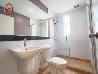 A modern bathroom with a glass shower enclosure, toilet, and sink.