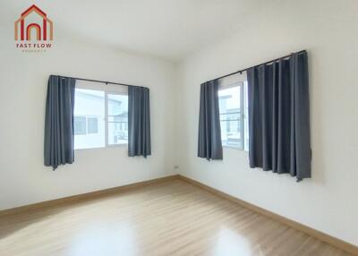 Empty bedroom with wooden floor and two windows with black curtains