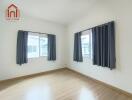 Empty bedroom with wooden floor and two windows with black curtains