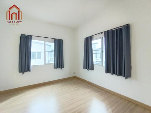 Empty bedroom with wooden floor and two windows with black curtains