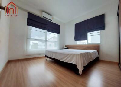 Modern bedroom with wooden flooring and large windows