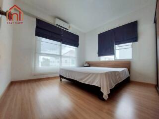 Modern bedroom with wooden flooring and large windows