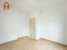 Empty bedroom with wooden flooring and white walls