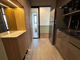 Modern kitchen with wooden cabinets, marble countertops, and view into a brightly lit room