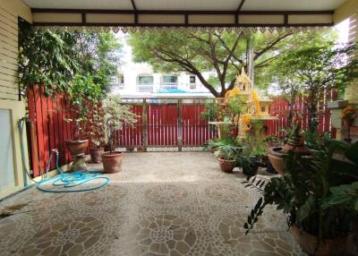 Covered patio area with potted plants, tiled floor, and a view of a fenced yard