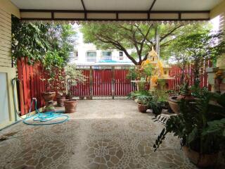 Covered patio area with potted plants, tiled floor, and a view of a fenced yard