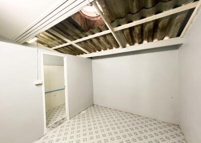 A bedroom with tiled flooring and exposed corrugated roofing