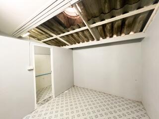 A bedroom with tiled flooring and exposed corrugated roofing