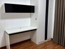 Simple bedroom with a wooden floor, white desk, white wardrobe, and a wall-mounted cabinet.