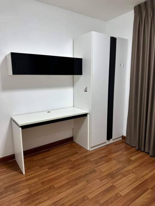 Simple bedroom with a wooden floor, white desk, white wardrobe, and a wall-mounted cabinet.