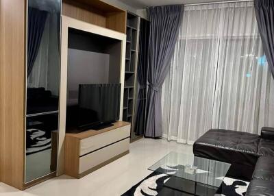 Modern living room with black leather sofa, media unit, and glass coffee table