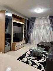 Modern living room with black leather sofa, media unit, and glass coffee table