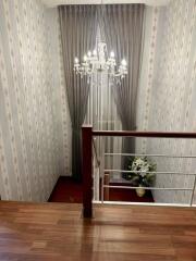 A view of a staircase with a chandelier and a floral arrangement