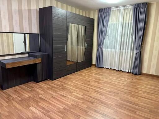 Spacious bedroom with wooden flooring and large wardrobe