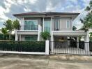 Two-story house with a tiled roof and gated driveway