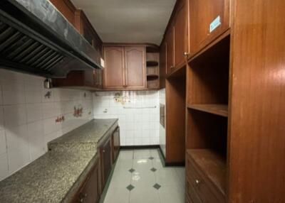 A kitchen with wooden cabinets, granite countertops, and tiled walls.