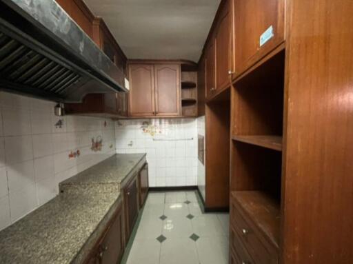 A kitchen with wooden cabinets, granite countertops, and tiled walls.