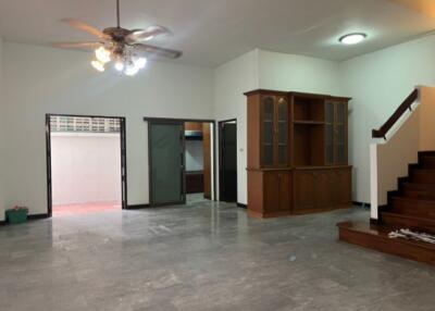 Spacious living room with ceiling fan, steps to a second floor, and a large wooden cabinet