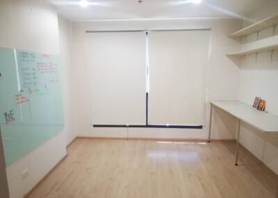 Empty room with wooden floor, whiteboard, shelves and a desk